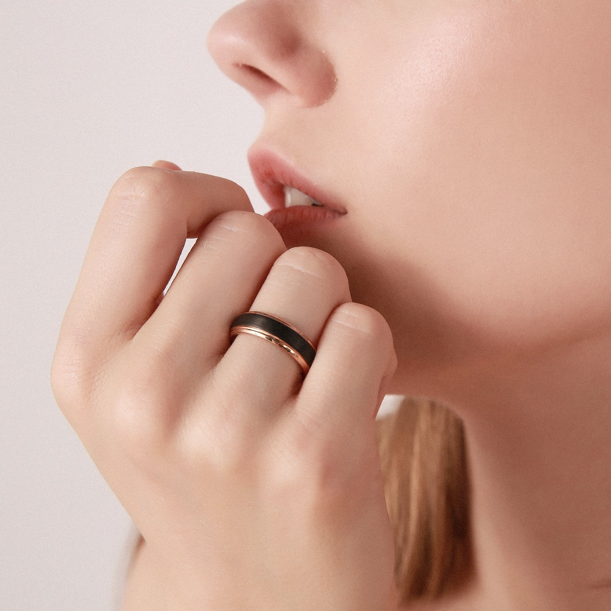Close-up of a hand wearing a black ring with a blurred background