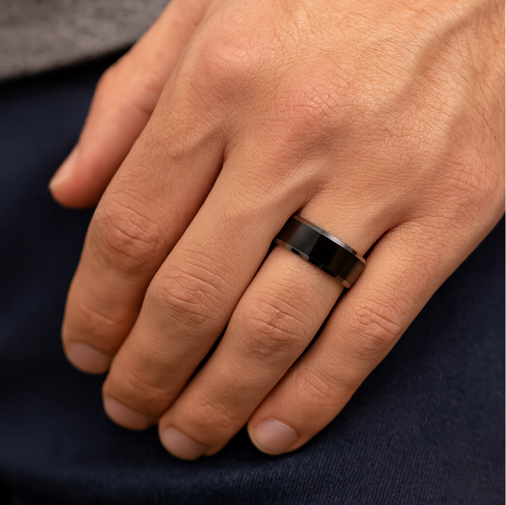 Hand wearing a black ring on a dark fabric background