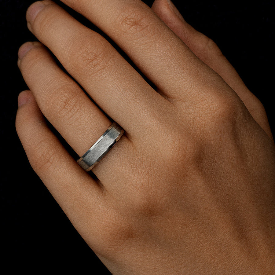 Hand wearing a silver ring on a black background