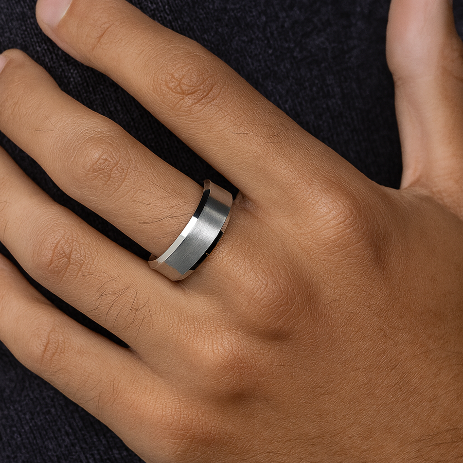 Hand wearing a silver ring on a dark background