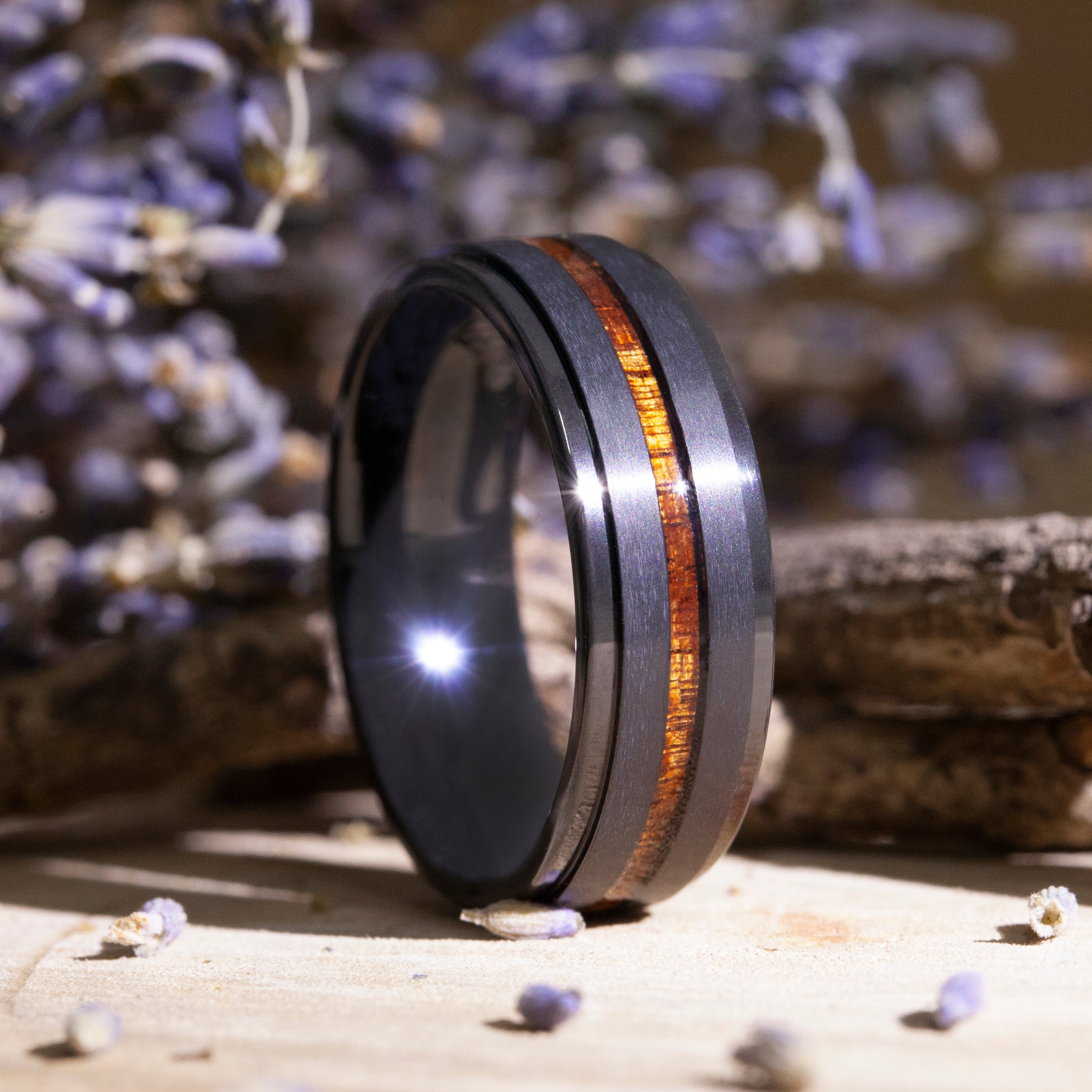 Black ring with wooden inlay on a textured surface with blurred background