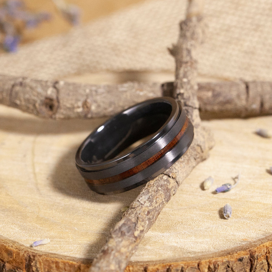 Black ring with wooden inlay on a wooden surface