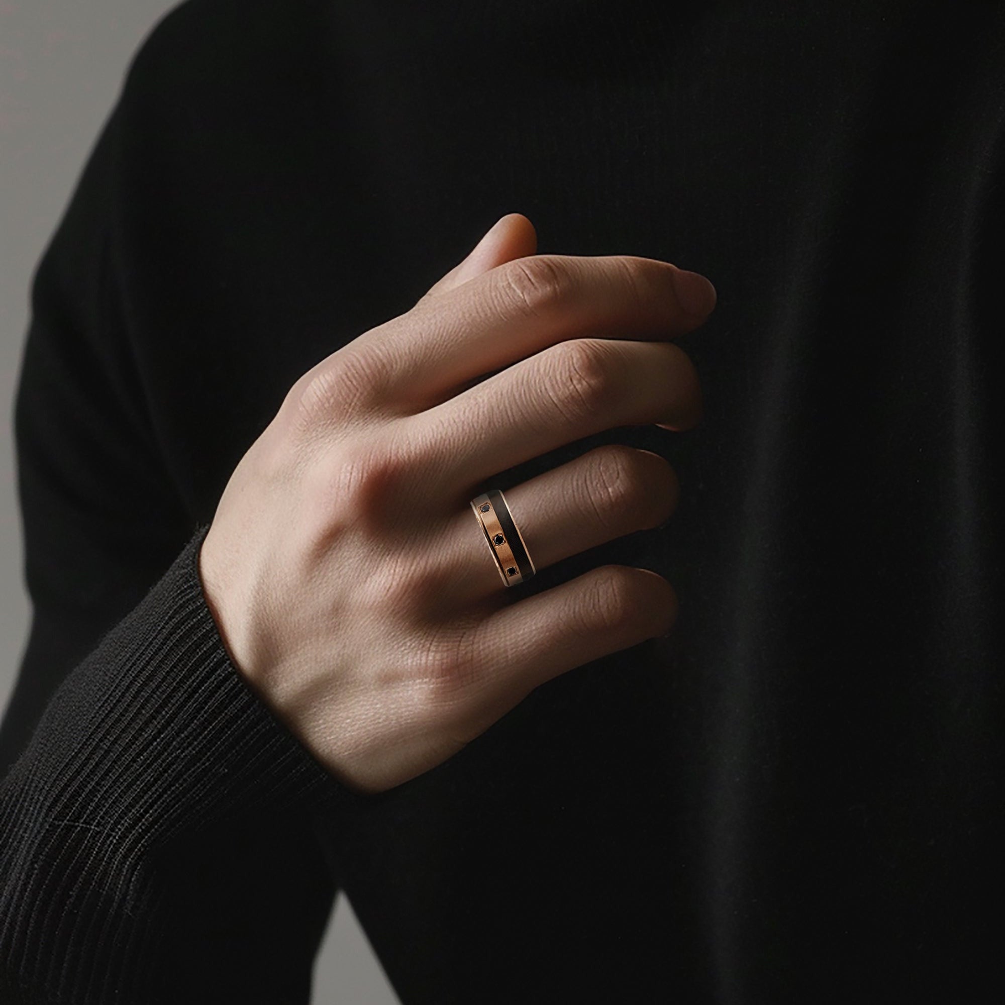 Person wearing a black turtleneck and a gold ring on a neutral background
