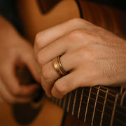 Close-up of a person's hand with a ring playing an acoustic guitar